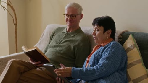 Senior Couple Relaxing Together Reading and Using Tablet