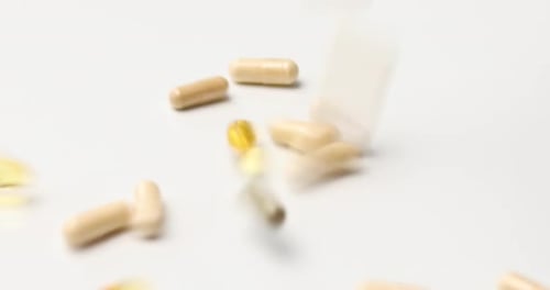 Pills Falling onto White Background for Health Content