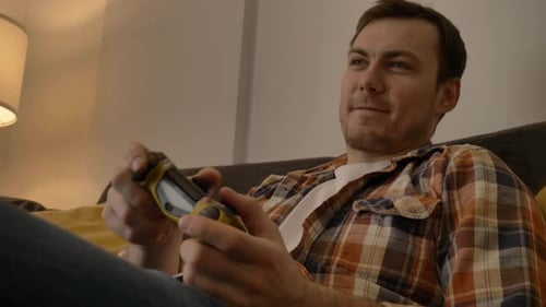 Man Playing Video Game on Couch Indoors