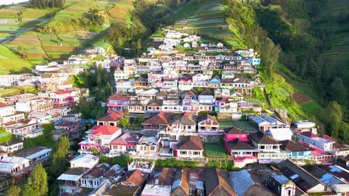 Toma de Zumbido hacia atrás del hermoso paisaje de un pueblo en la ladera de la montaña con vista a una h en terrazas