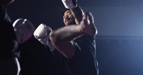 Un combattant de Muay Thai décroche un coup de pied haut, son rival parie habilement lors d'un match de boxe professionnel