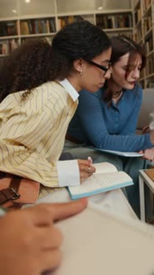 Vertical of Diverse Female Students Working on Project Together in Library