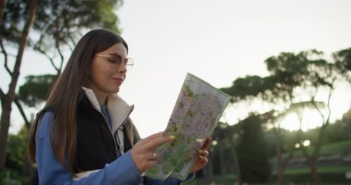 Woman Using Map To Navigate Through City Park