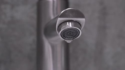 Gros plan d'un robinet d'eau qui goutte à goutte : problèmes de plomberie et conservation de l'eau