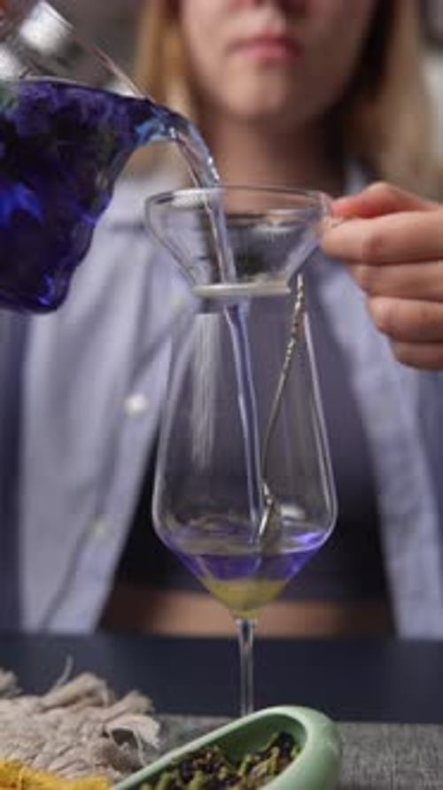 Person Pours Blue Drink into Wine Glass