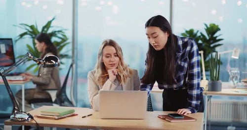 Two Women Collaborating on Laptop in Office