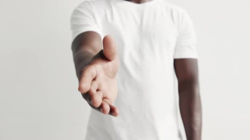 Hombre dando el brazo extendido para un primer plano con un apretón de manos. Chico negro milenario estirando
la mano