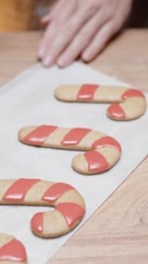 Vertical video. The woman is making homemade gingerbread cookies and decorating them with icing.
