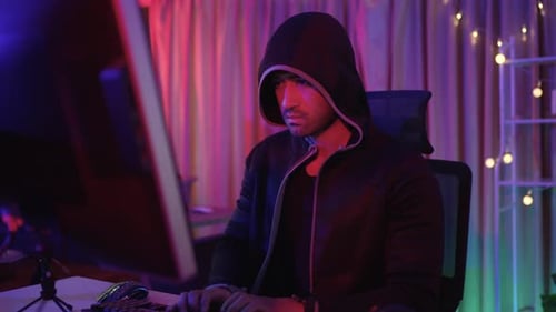 Hooded Young Adult Typing on Computer Keyboard