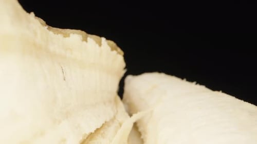 Banana and peel on a black glass table. Dolly slider extreme close-up. Laowa Probe