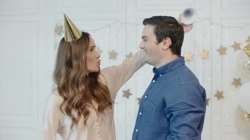 Couple celebrates with golden party hats and balloons
