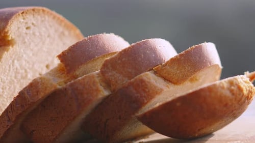Slices of Freshly Baked Homemade White Bread on Wooden Chopping Board Outside in Natural Morning.