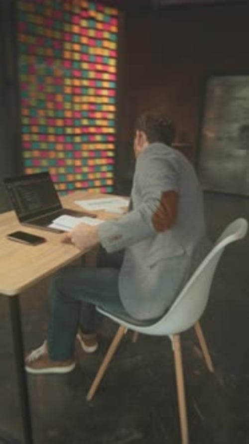 Mann arrangiert Notizen kaukasisch, individuelle Positionierung lebendiger Noten an der Wand während des konzentrierten Studios