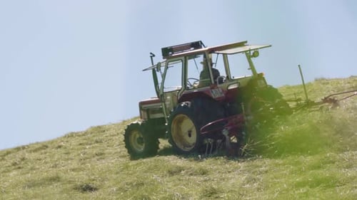 Zeitlupe eines alten Traktors mit Landwirt, der nach der Ernte auf dem Feld fährt
