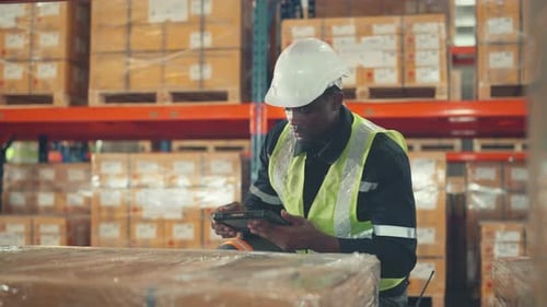 African American man worker checks products stock inventory with digital tablet in the warehouse