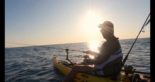 Practica kayak en la playa remando y pescando. Kayakista pescando en el mar Mediterráneo durante el verano