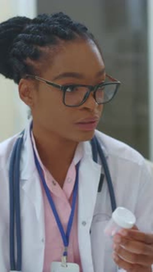 Woman Doctor Examines Prescription Bottle in Hospital