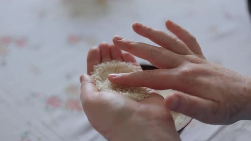 Hands Inspecting and Sorting Uncooked White Rice