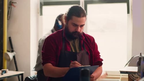 Craftsperson Drawing Blueprints in Studio Next to Coworker