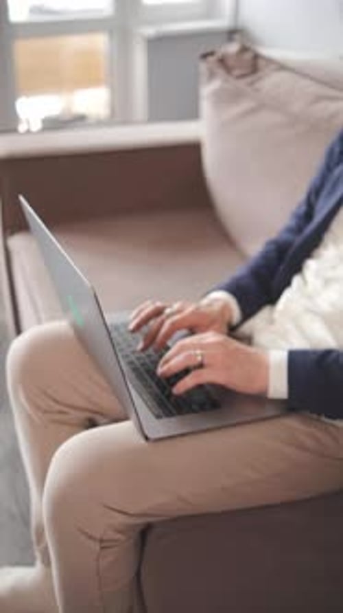 Curly Focused Business Man in a Jacket and Pajama Pants Working on Laptop Sitting at Home Office