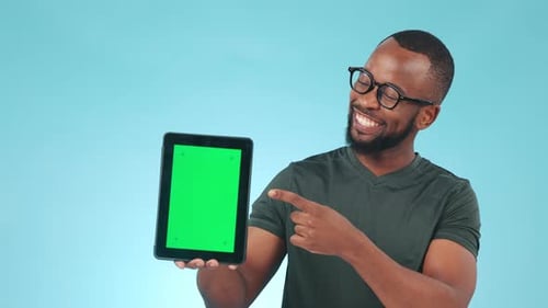 Hand, green screen and pointing to a tablet with a black man in studio on a blue background