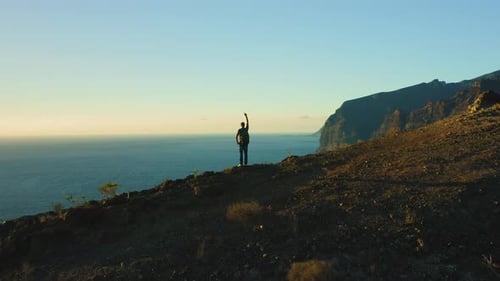 Hiker Enjoys Ocean View at Top of Mountain Hands Up in the Air