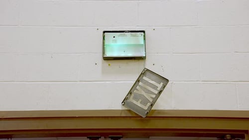 Foto de mano de una señal de salida dañada colgada en la parte superior de la puerta del gimnasio