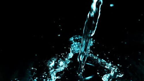 A stream of water falls and creates a splash on a black background. Slow motion.