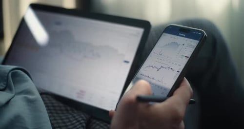 Close Up of Businessman Working on Smartphone and Tablet Displaying RealTime Stocks in Trading App