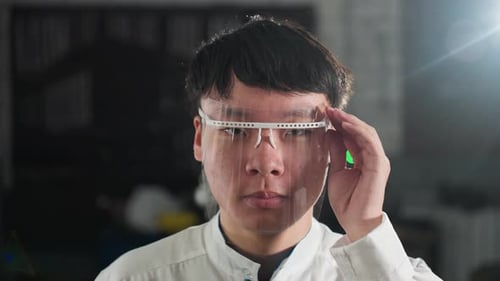 Automobile Engineer Adjusting Protective Glass in Automotive Workshop with Green Light