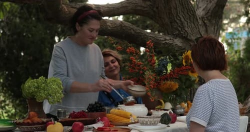 Woman Serving Soup at Outdoor Meal with Friends