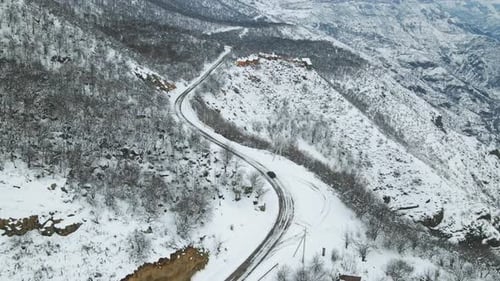 Luftflug in der Winterlandschaft Schwarzes Auto fährt auf der winterbedeckten verschneiten Straße dazwischen