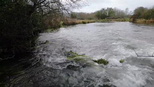 Fast flowing River tumbling over rocks with high water level just short of flood