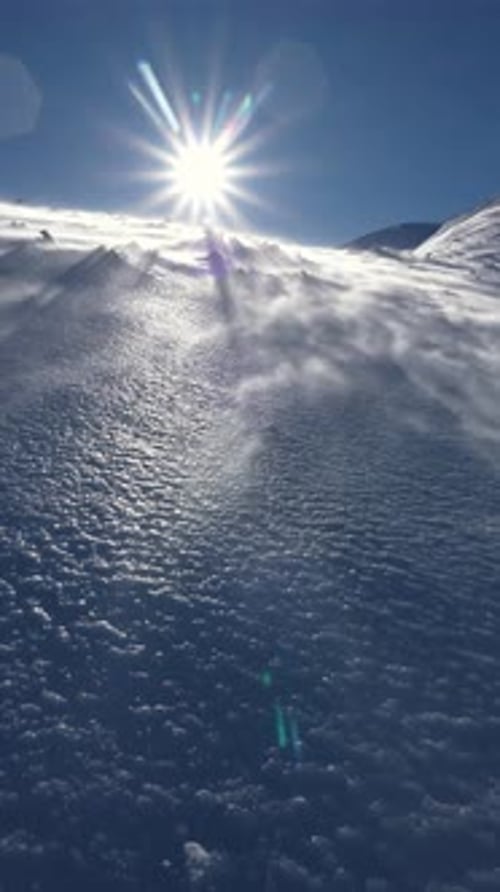 Wind Blowing Snow Downhill in Winter Alpine Mountains in Sunny Windy Day Vertical Video
