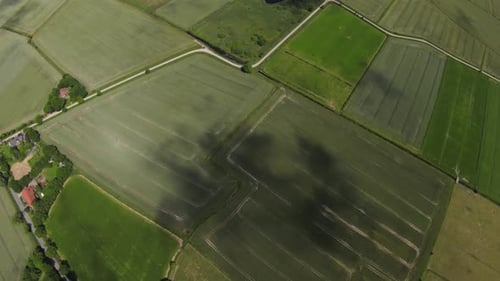 drone shot of a shadow of a cloud moving slowly over green fields