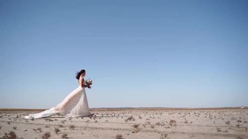 Pretty Woman in Gorgeous Wedding Dress Walking at Desert Landscape Windy Weather Elegance Bride with
