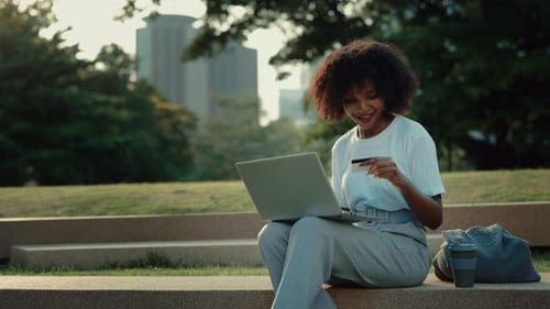 Portrait of African American Woman Enjoying Shopping Via Laptop in Urban Park