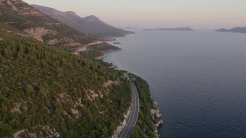 Aerial view of coastal road winding through mountain range at dusk, Croatia.