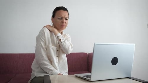 Woman Massaging Stiff Neck at Home Near Computer