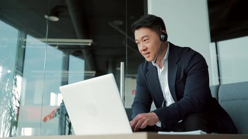 Man in Jacket Works on Laptop with Headset