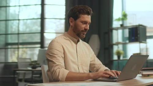 Entrepreneur Man Sitting at Desk Use Laptop Look on Screen Smiling Feel Happy in Office Satisfied