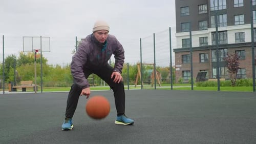 Basketball Practice Scene Man Practicing Ball Handling on Urban Basketball Court Solo Athlete