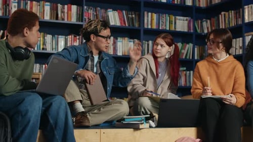 Motivated Diverse Students Discussing Books in Modern Library