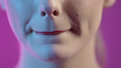 Nahaufnahme von Gesicht und Mund einer Frau mit rotem Lippenstift auf ihren Lippen vor lila Hintergrund, Studio S
