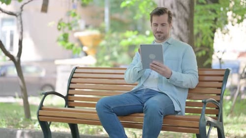 Man Using Tablet on Park Bench