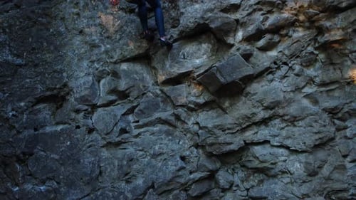 Woman Rappelling Down a Rocky Cliff Face