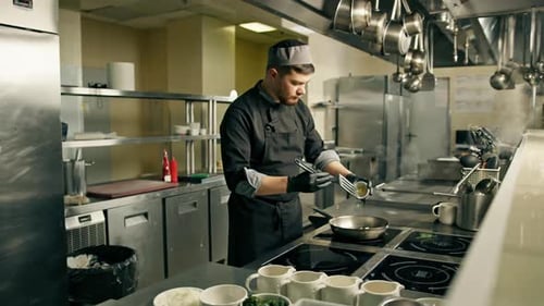 professional kitchen in the restaurant the chef prepares a risotto dish adds ingredients to the pan