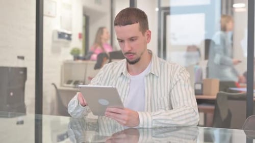 Young Adult Man Using Tablet in Office Setting