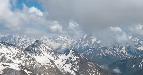 Air flight through mountain clouds over beautiful snow-capped peaks of mountains and glaciers.