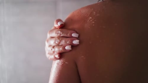 Woman Gently Rubs Shoulder in Shower Close Up